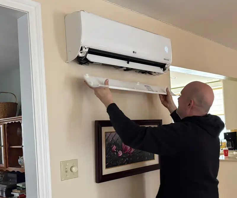 Ryan Backman performing maintenance on an indoor heat pump head unit