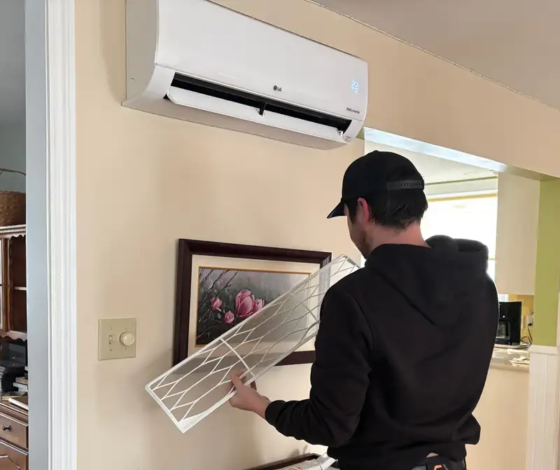 A technician cleaning an interior heat pump head unit.