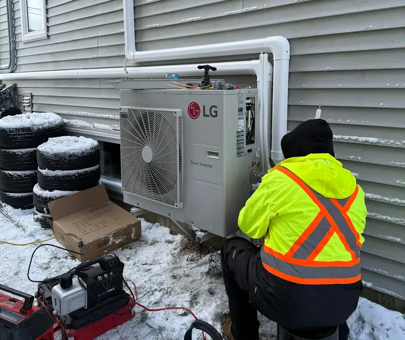 A Backman technician servicing an outdoor heat pump unit during a maintenance appointment