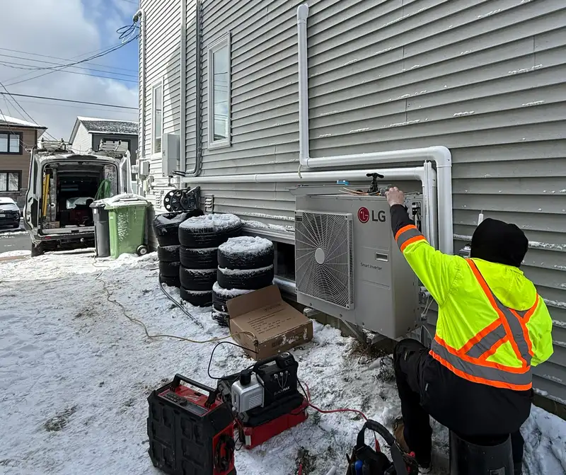 A Backman technician servicing an outdoor heat pump compressor unit during a repair appointment